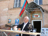 Sheki / Shaki - Azerbaijan: man recruiting for target practice - Azeri flag and the Aliyevs in the background - photo by N.Mahmudova