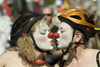 Vancouver, BC, Canada: two women with clown noses and bicycle helmets - participants in the Gay Pride Parade - kiss - photo by D.Smith
