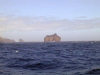 Crozet islands - Possession island: Roche Percee (Pierced Rock) stands off shore, with the triangular Roches des Moines (Friars' Rocks) to the left (photo by Francis Lynch)