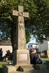 Castleton, Peak District, Derbyshire, England: couple sitting beside Celtic cross - photo by I.Middleton