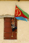Eritrea - Hagaz / Agaz, Anseba region - boy placing the flag of Eritrea on a house - photo by E.Petitalot