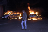 Germany - Berlin: riots on May 1st - pedestrian passes burning cars - photo by W.Schmidt