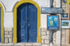 Greece, Kastellorizo: brightlypainted wooden door and signs on a harbourside building - photo by P.Hellander