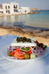 Greece - Paros: Greek Salad in table in foreground with background Naousa beach - photo by D.Smith