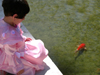 Israel: small girl dressed-up for the Purim celebrations, watching the fish in a pond - photo by E.Keren