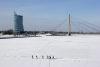 Latvia / Latvija / Lettland - Riga: frozen Daugava - crossing the river - Saules Akmens building and Vansu bridge in the background - walking on the ice - photo by Alex Dnieprowsky