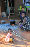 West coast road between the Manambolo river and Belon'i Tsiribihina, Toliara Province, Madagascar: Sakalava woman and her two daughters - cooking a meal outside the house - photo by M.Torres