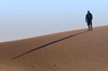Namibia: Man on sand dune casting long morning shadow, Skeleton Coast - photo by B.Cain