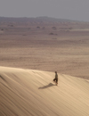 Namibia: Man walking on sand dune, Skeleton Coast - photo by B.Cain