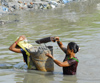 Kathmandu, Nepal: women extract back sand in a polluted river - photo by E.Petitalot