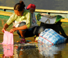 Pokhara, Nepal: a mother washing clothes in Phewa lake with her baby on the back - photo by E.Petitalot
