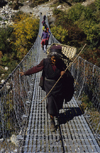 Annapurna area, Nepal: woman with bamboo basket crossing a suspension bridge - photo by W.Allgwer