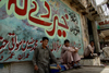 Peshawar, NWFP, Pakistan: mural and idle men - photo by G.Koelman