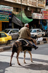 Hebron, West Bank, Palestine: man rides a donkey in street - photo by J.Pemberton