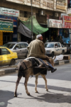 Hebron, West Bank, Palestine: man rides a donkey in street - photo by J.Pemberton