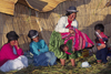 Lake Titicaca, Puno region, Peru: Aymara woman hoists baby at a wedding celebration on the main floating island - women with typical hats - photo by C.Lovell