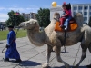 Russia - Kyzyl (Tuva / Tyva republic): children riding a Bactrian camel  in the central square (photo by A.Kilroy)