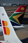 Johannesburg, Gauteng, South Africa: A340 and A330 aircraft tails - Iberia and South African Airways - Iberia Airbus A340-313, EC-GHX 'Rosalia de Castro' and South African Airways Airbus A330-243 ZS-SXX - OR Tambo International / Johannesburg International Airport / Jan Smuts / JNB - Kempton Park, Ekurhuleni - photo by M.Torres