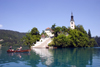Slovenia - Couple rowing past church of the Assumption on Lake Bled - photo by I.Middleton