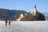 Slovenia - people walking across ice - island church on Lake Bled in Slovenia when frozen over in winter - photo by I.Middleton
