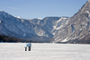 Slovenia - Couple walking across Bohinj Lake / Wocheinersee when frozen over - view towards Ukanc - photo by I.Middleton