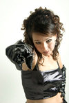 Young woman in a glamorous fashion pose wearing a black vinyl dress and black gloves while pointing at the camera with a threatening look - photo by D.Smith