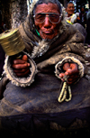 Tibet - pilgrims worshipping - elderly man with prayer wheel and beads - photo by Y.Xu