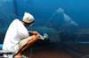 Port of Spain, Trinidad: worker polishing the hull of a sailing boat - photo by E.Petitalot