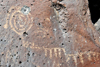 Albuquerque, Bernalillo County, New Mexico, USA: Petroglyph National Monument - Rinconada Canyon trail - bullet-damaged spiral - petroglyph made by pecking the basalt - photo by M.Torres