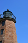 Point Judith, Narragansett, Rhode Island: Point Judith Lighthouse with the light on the fresnel lens against ble sky - entrance to Narragansett Bay -  octagonal granite tower and sky - photo by M.Torres