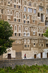 Sana'a / Sanaa, Yemen: child walking along wall in front of Old City houses - ancient skyscrapers - UNESCO World Heritage Site - houses with elaborate exterior ornamentation - photo by J.Pemberton