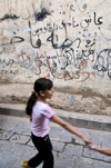 Sana'a / Sanaa, Yemen: girl in front of graffitied wall - Arabic characters - photo by J.Pemberton